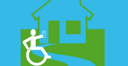 Rollstuhlfahrer mit Fernbedinung vor einem Haus